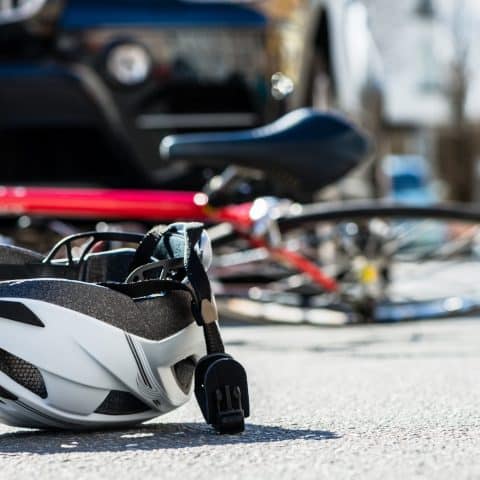 Primer plano de un casco de bicicleta sobre el asfalto al lado de una bicicleta