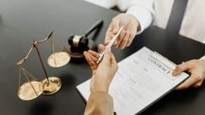Concepto de derecho laboral. Abogado firmando documento legal con el mazo del juez.