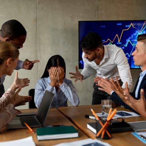 Acoso Laboral. Compañeros Agresivos Gritando A Una Mujer Asiática Estresada En La Oficina