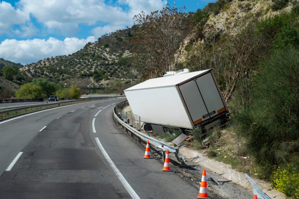 Camión frigorífico que ha sufrido un accidente al salirse de la carretera, dejándolo fuera de la carretera pero sin volcar.