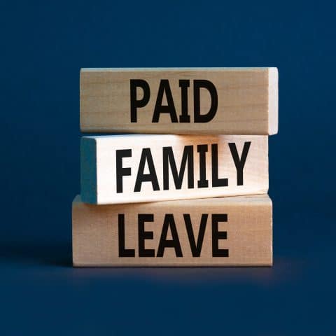 Símbolo de licencia familiar remunerada. Palabras conceptuales Licencia familiar remunerada en bloques de madera. Hermosa mesa gris con fondo gris. Concepto de negocio médico y licencia familiar remunerada. Espacio para copiar.