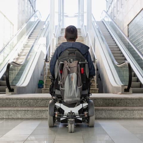 Hombre con discapacidad en silla de ruedas detenido frente a una escalera