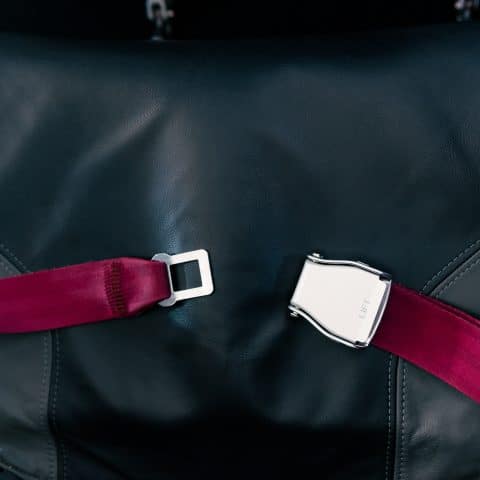 Cinturón de seguridad rojo en avión sobre asiento negro. Desbloqueado. Seguridad, prevención de accidentes.