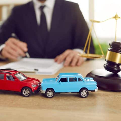 Primer plano de dos coches de juguete sobre el fondo de un juez que está dirigiendo un juicio por un accidente de tráfico.