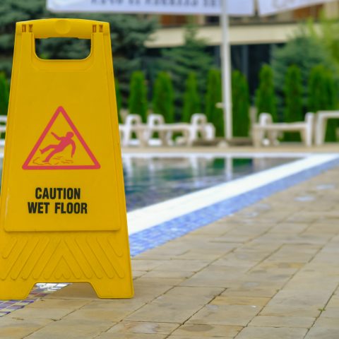 Advertencia de piso mojado cerca de la piscina en el hotel.