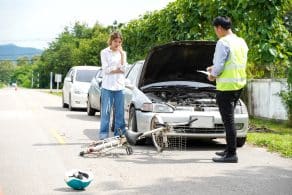 Un agente de seguros está preguntando a una conductora sobre un accidente de bicicleta en la carretera.