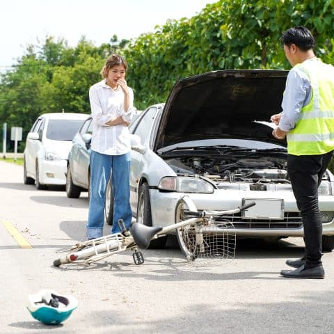 Un agente de seguros está preguntando a una conductora sobre un accidente de bicicleta en la carretera.