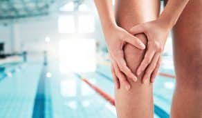 Lesión deportiva, dolor de rodilla y espacio con una persona en una piscina para acondicionamiento físico, entrenamiento y salud. Primeros auxilios, emergencia y accidente con primer plano de un nadador para dolor muscular, inflamación en la pierna o modelo.
